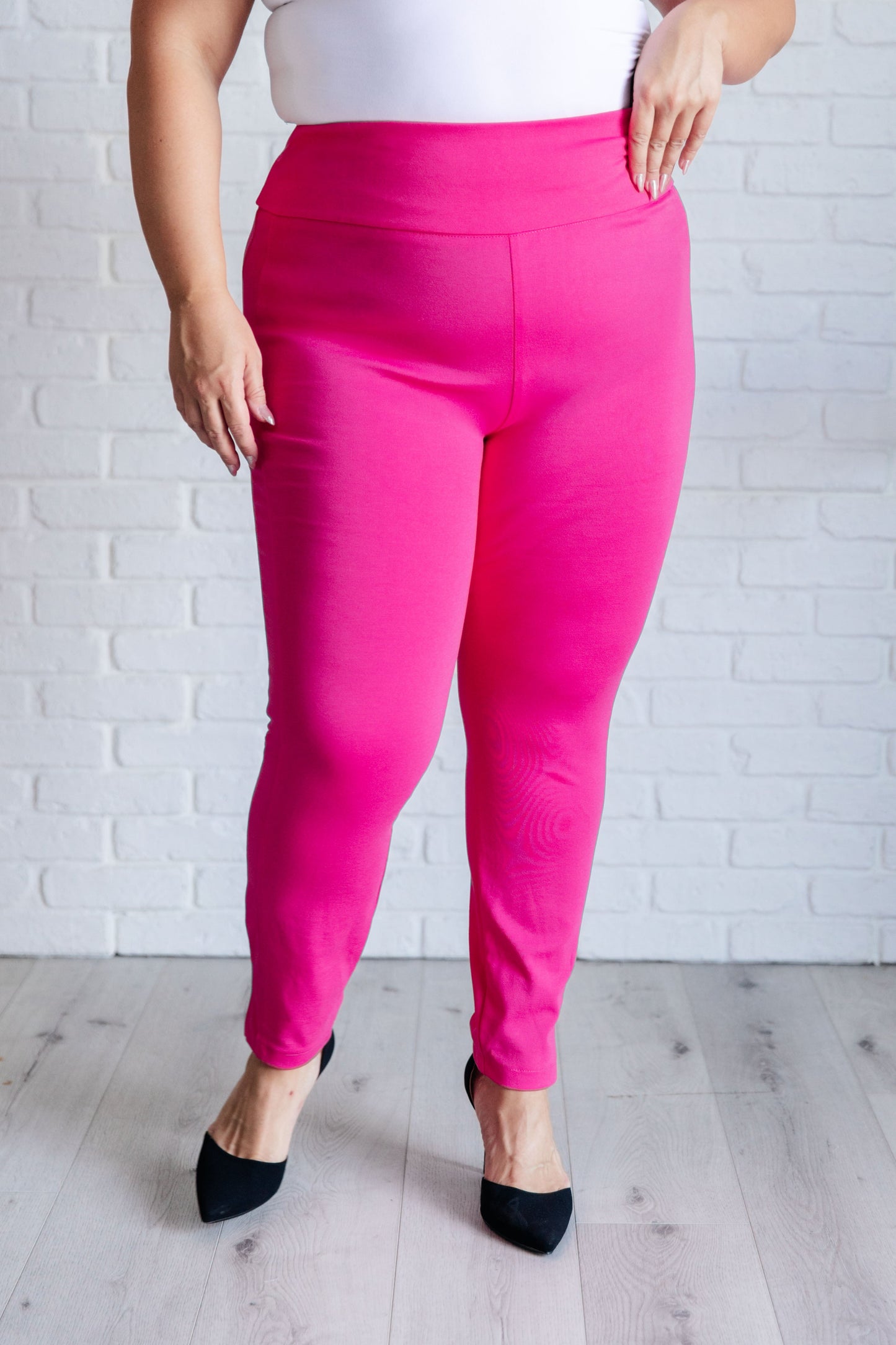 Plus-size model in hot pink skinny pants with high-rise waist and slimming tuxedo stripe detail.