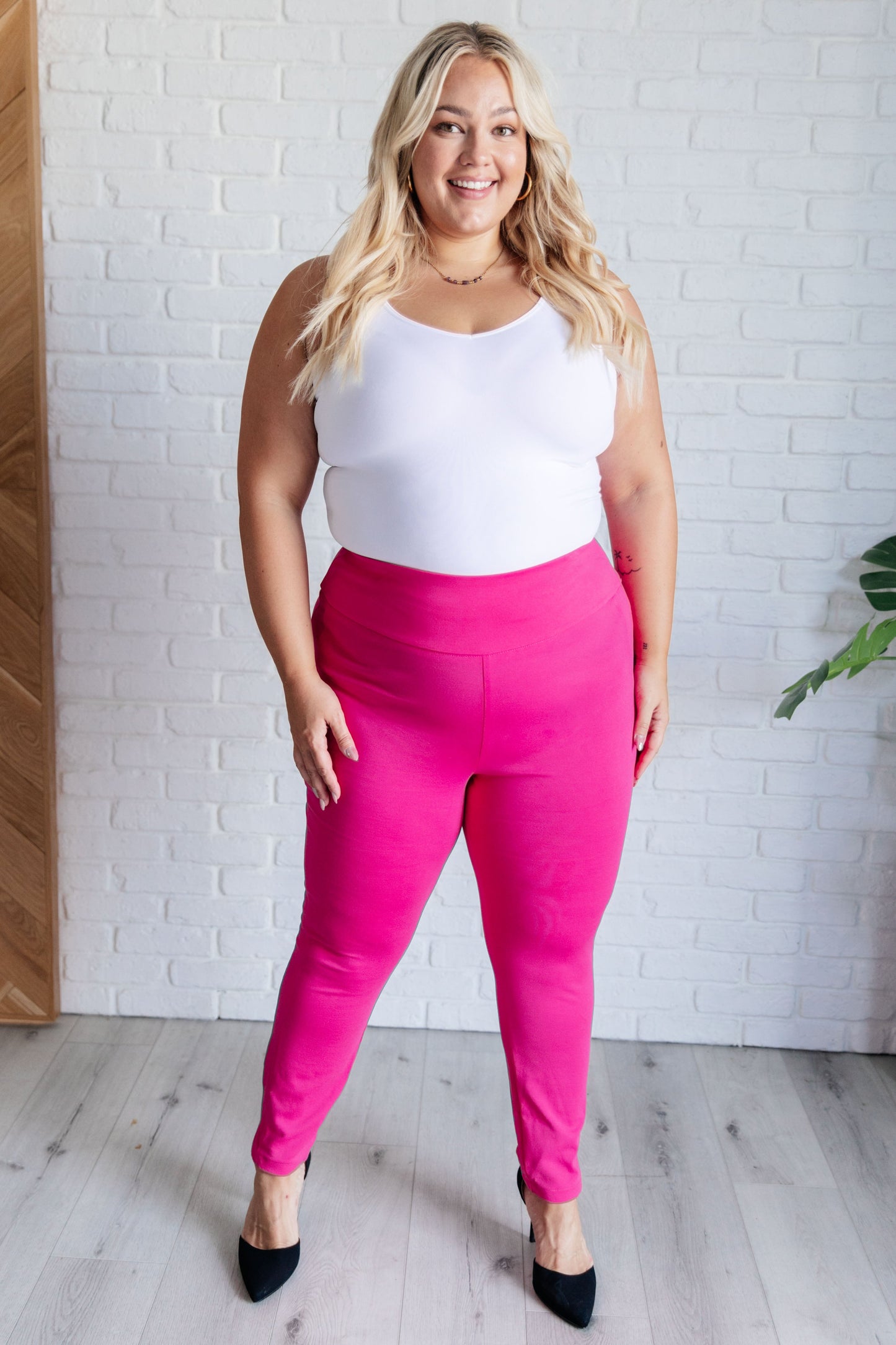 Plus-size full body view of hot pink skinny pants with elastic waistband and faux welt pocket accents.