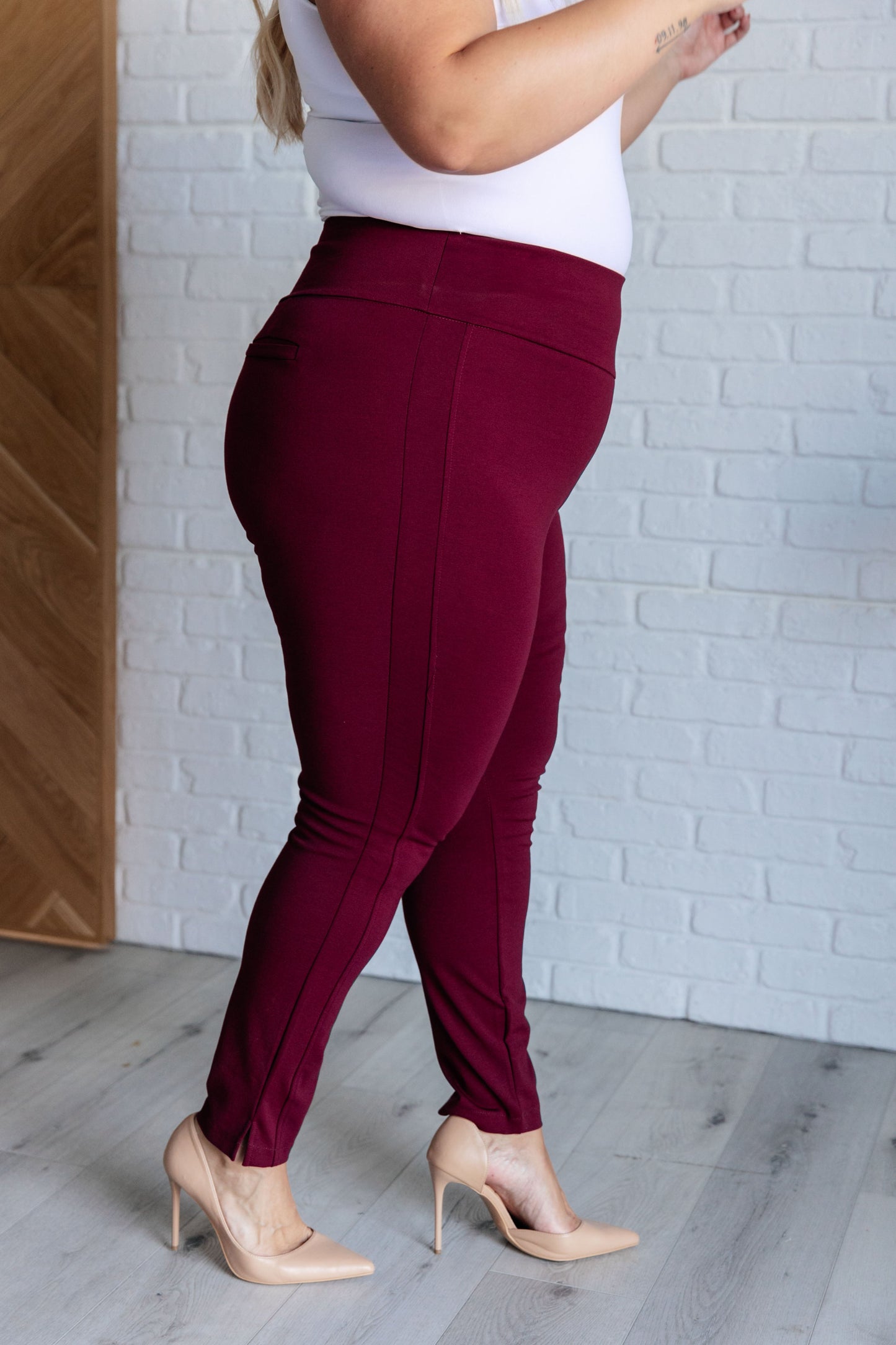 Plus-size model side angle in wine skinny pants with slimming tuxedo stripe detail.