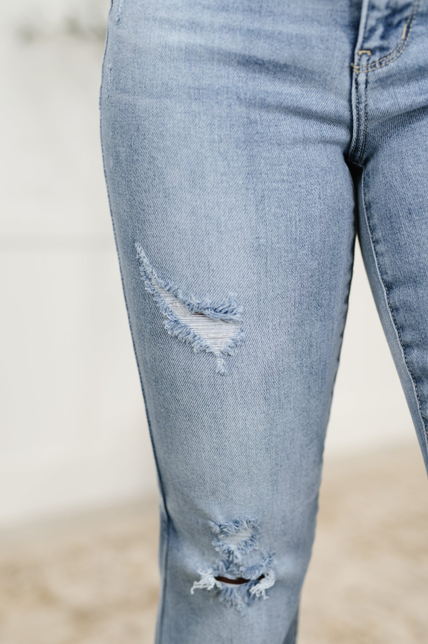 Close-up of Marlena High Rise Flare Jeans highlighting slight distressing and raw hemline in light wash denim.