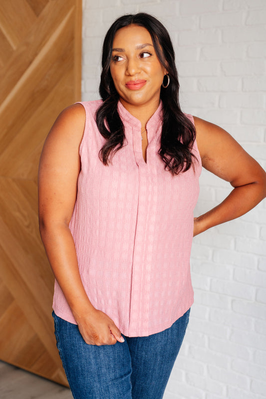 Plus-size model in Eva pink sleeveless blouse with front pleats and split neckline detail.