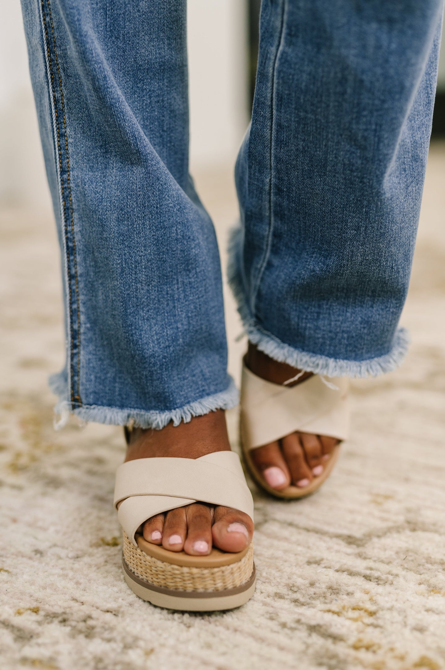 Close-up of Maureen bootcut jeans showing raw frayed hem and bootcut silhouette in medium wash denim.