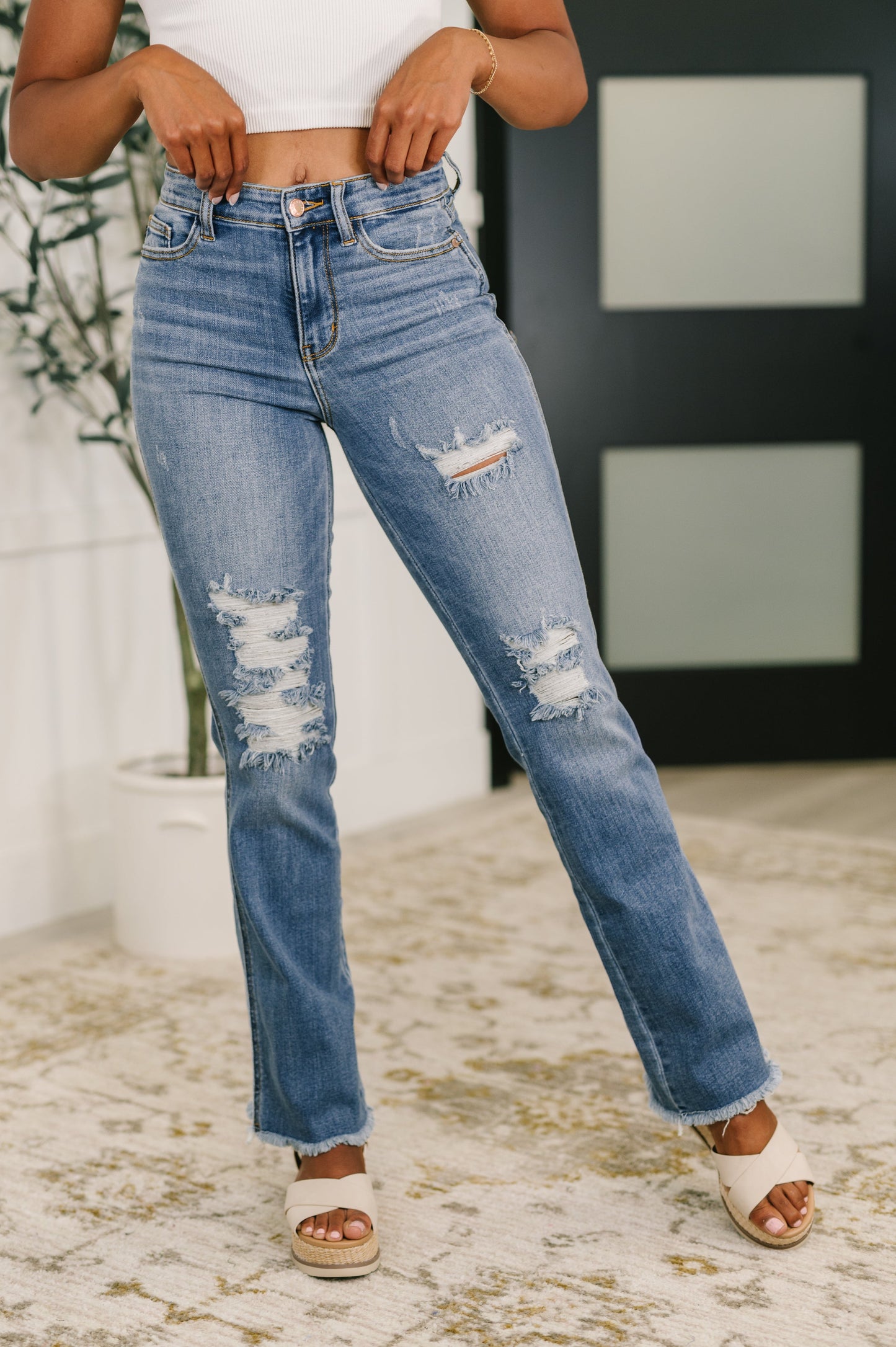 Front view of Maureen high rise bootcut jeans with distressed detailing and frayed hem in medium wash denim.