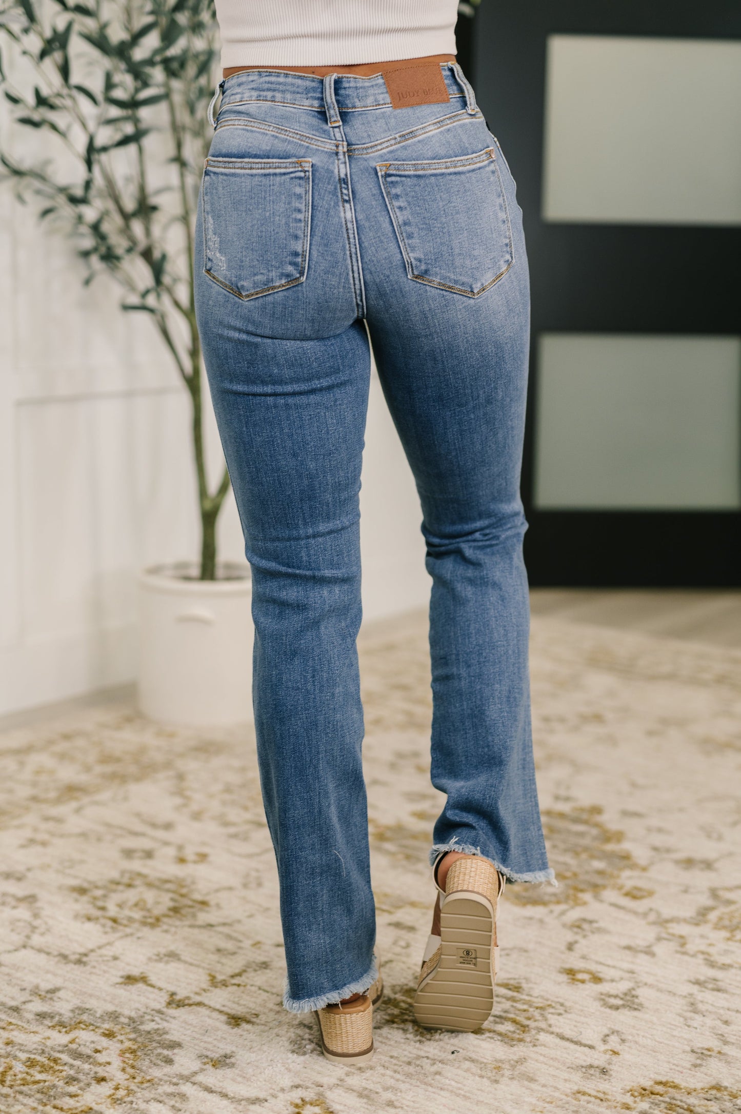 Back view of Maureen high rise bootcut jeans featuring classic pockets, flattering yoke, and medium wash denim with frayed hem.