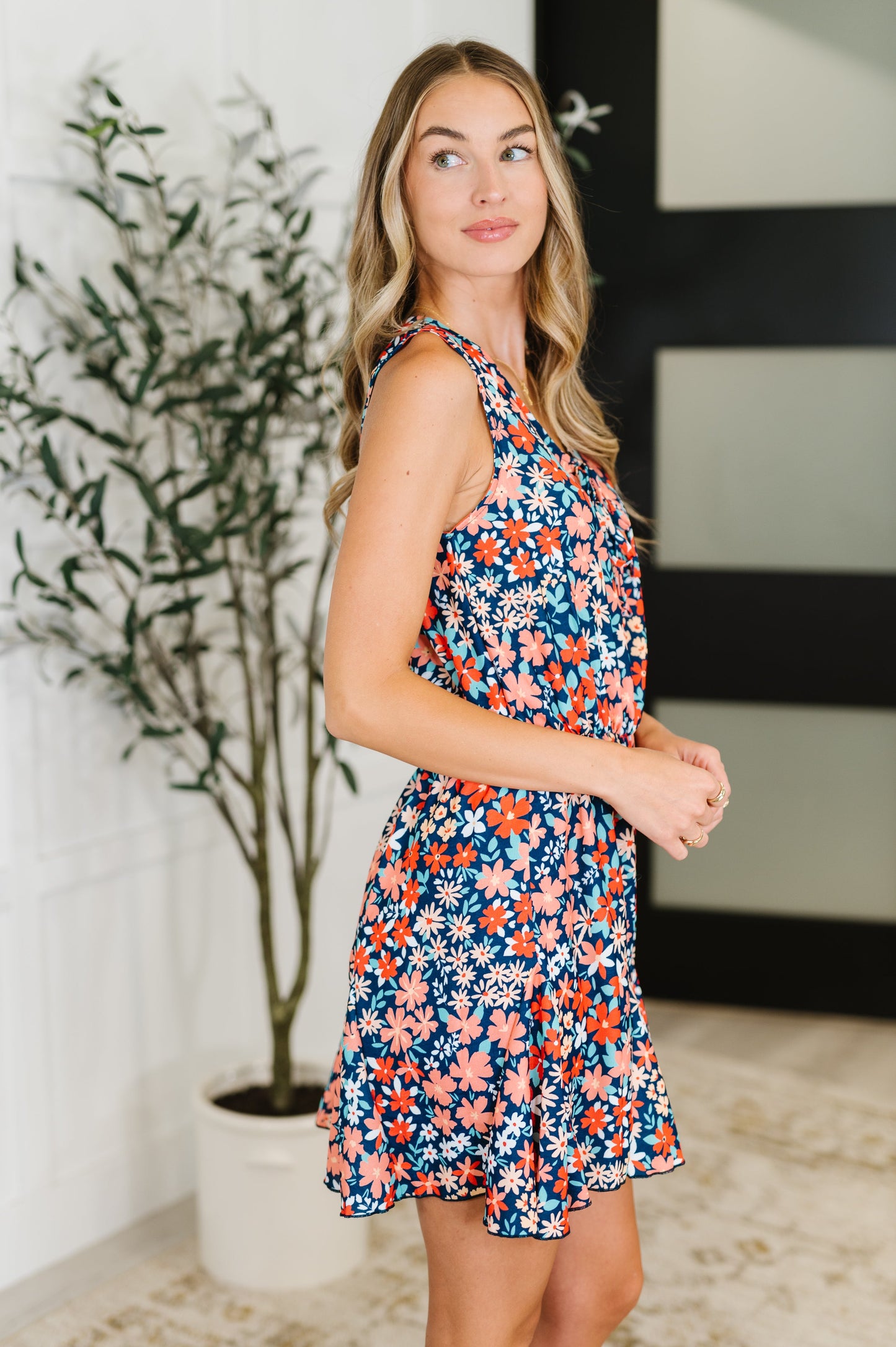 Side view of Meadow navy floral romper featuring sleeveless design, elastic waistband, and flouncy godet detail.