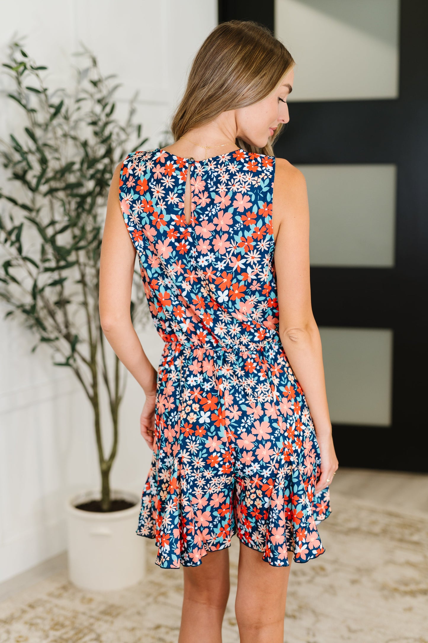 Back view of Meadow floral romper showing sleeveless cut, elastic waist, and cute keyhole closure.