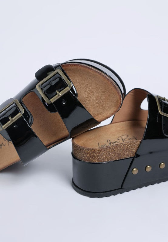 Angled view of Merton Studded Slip Ons with chunky 1.5 inch flatform heel, shiny patent black finish, and open toe.