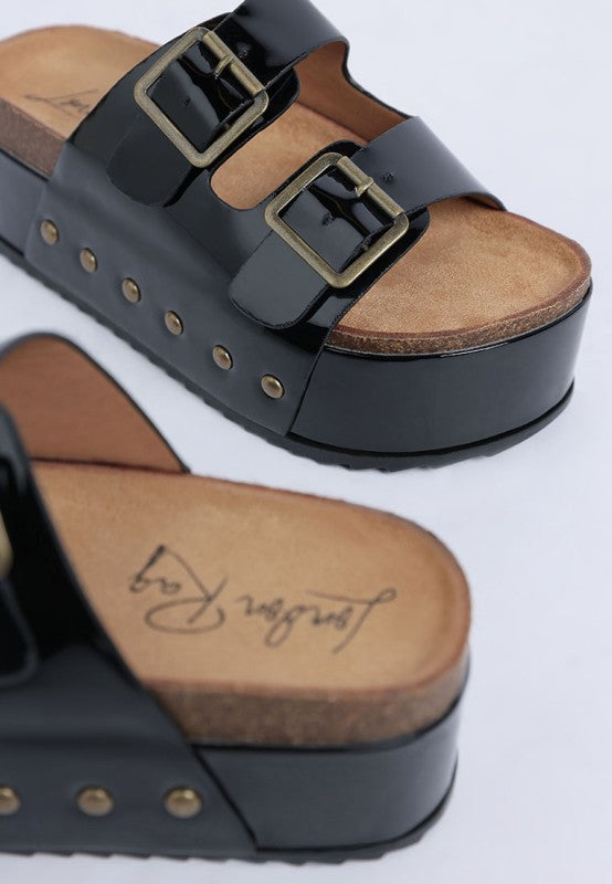 Side angle of black Merton Studded Slip Ons featuring shiny patent upper, open toe, and bold stud embellishments.