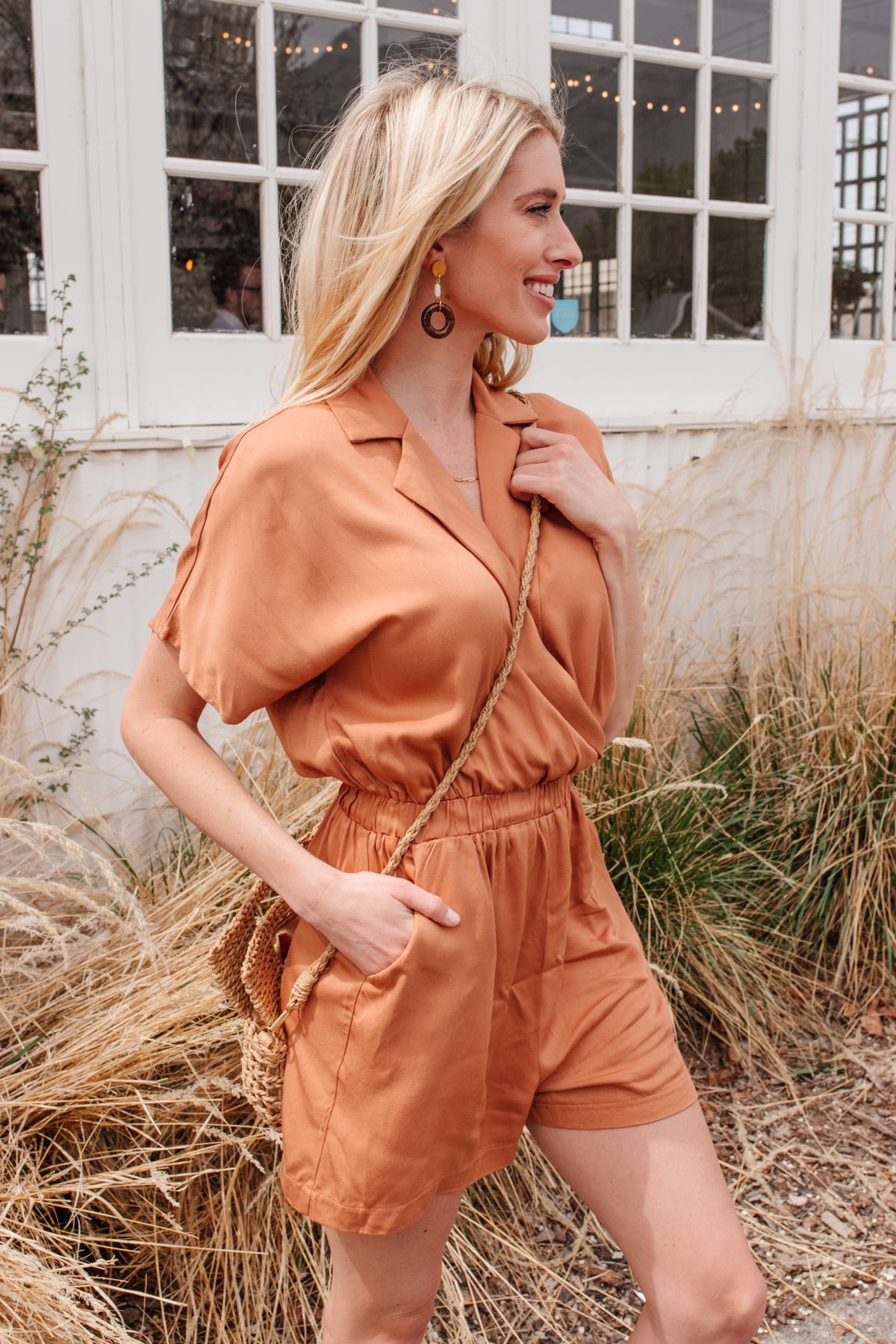 Camel-colored romper with a collared V-neckline, short sleeves, an elastic waistband, and functional pockets.