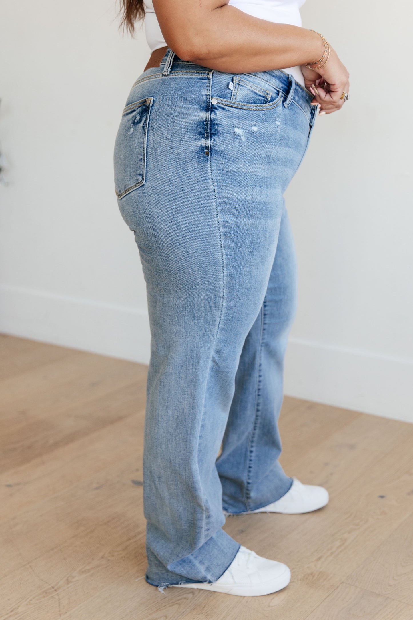 Plus size side view of Mildred V-Front Straight Jeans showing raw hem and stretch fit.
