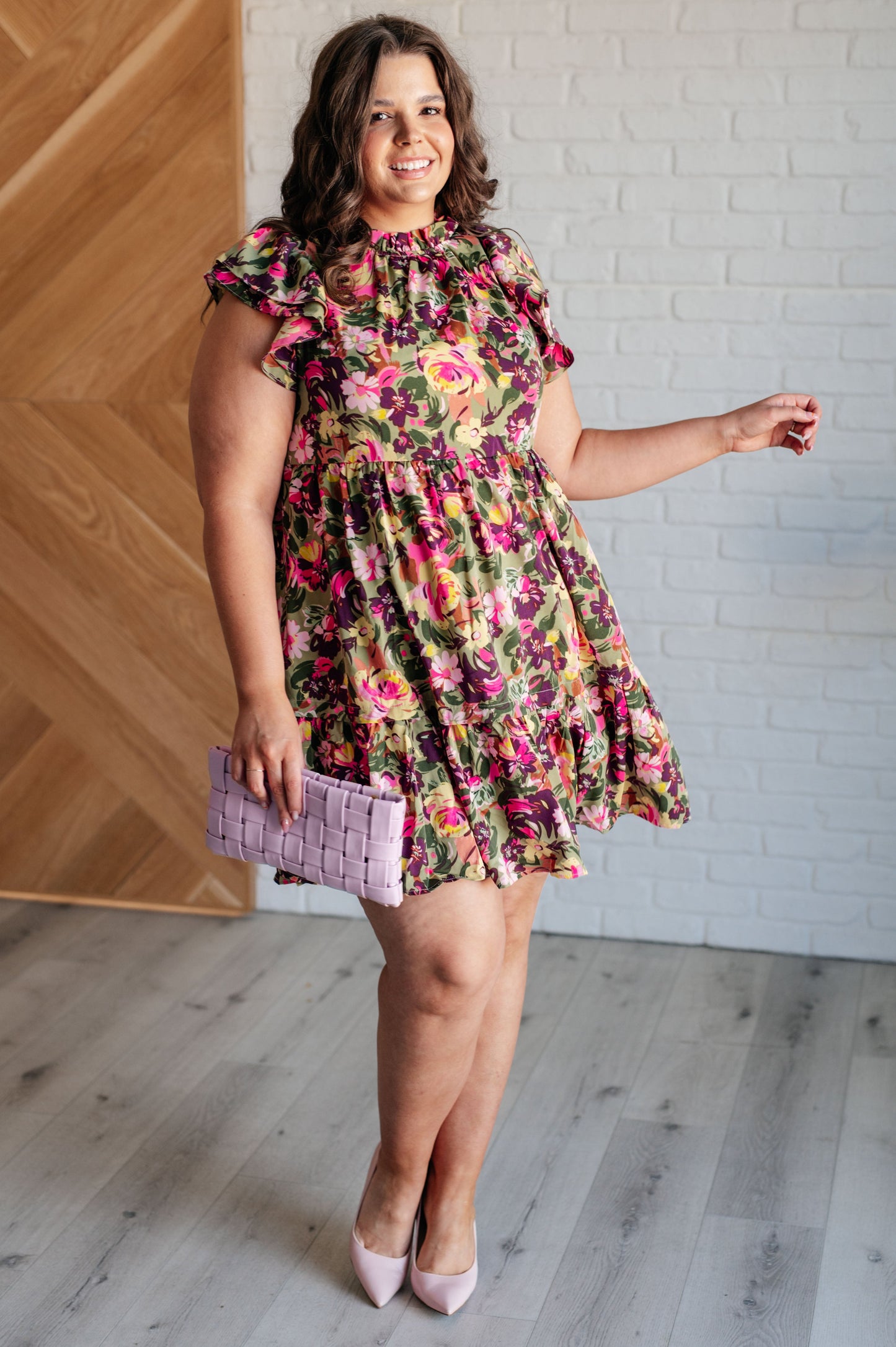 Plus size model wearing Nita Floral Woven Dress full body view, showing ruffled mock neck and flutter sleeves.