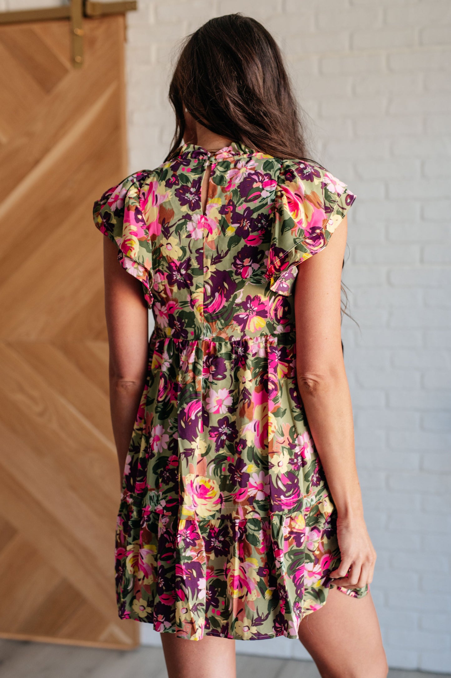 Back view of Nita Floral Woven Dress, showing keyhole button closure and flowy ruffle hemline.