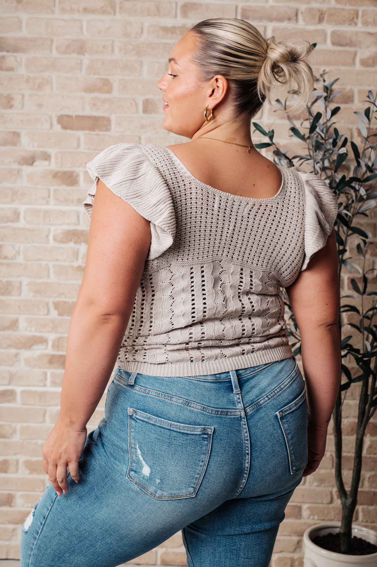 Plus size styling of greige pointelle knit top with flutter sleeves and soft sweater knit.