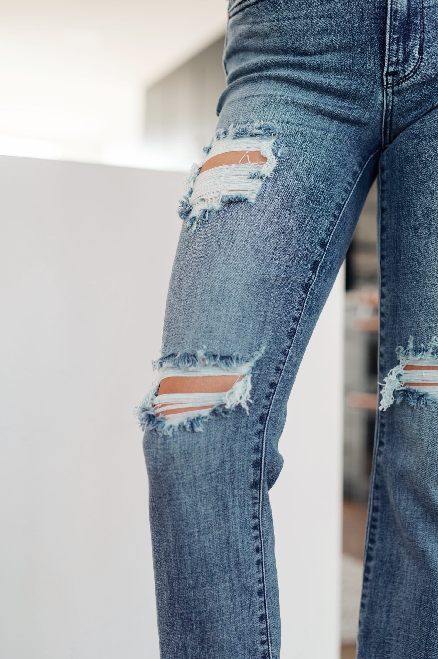 Close up of pant leg distressing on O’Hara Judy Blue destroyed straight jeans in medium wash