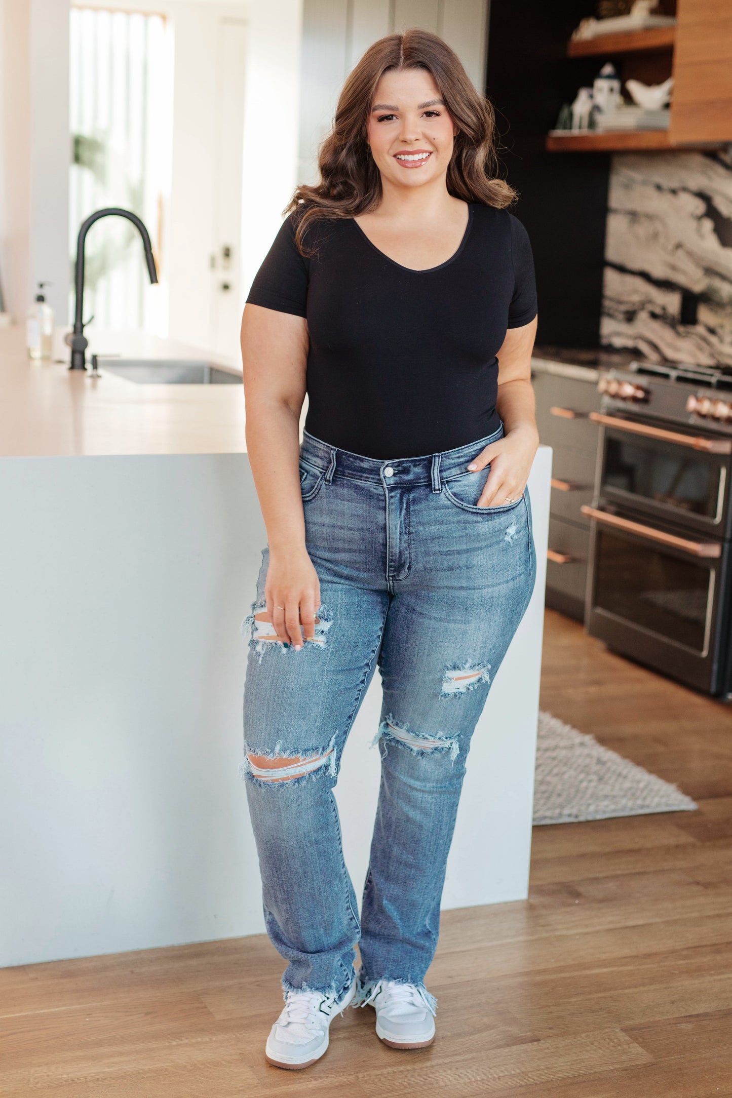 Plus size full body view wearing O’Hara Judy Blue mid-rise destroyed straight jeans with raw hem