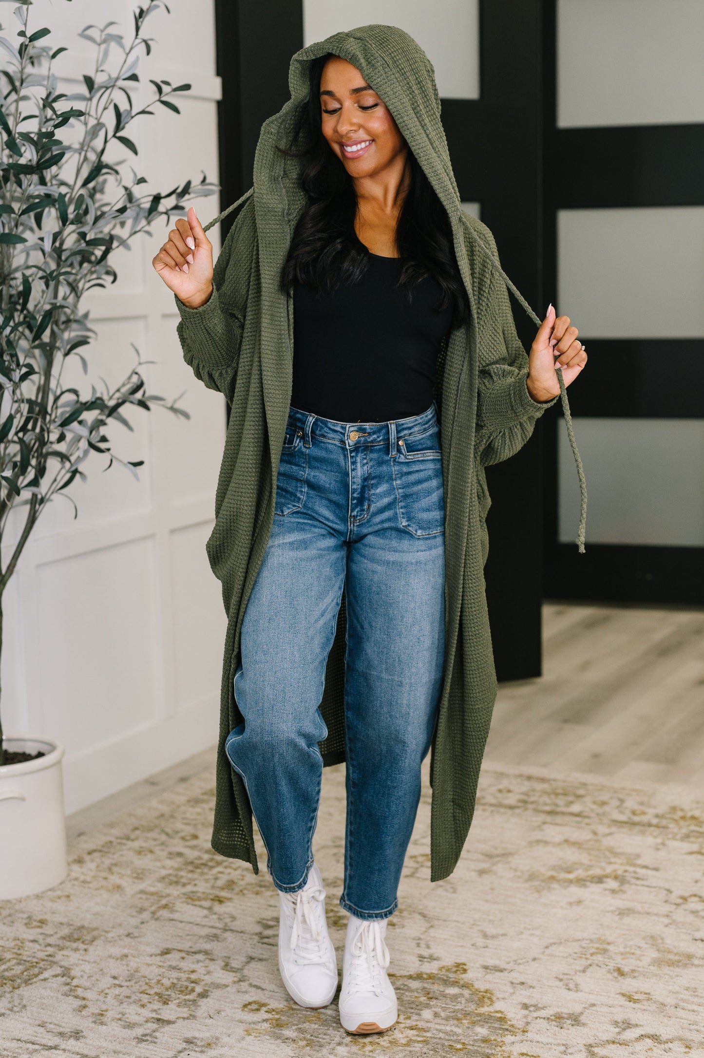 Model wearing Remington Hooded Cardigan in olive with hood up and open front style.