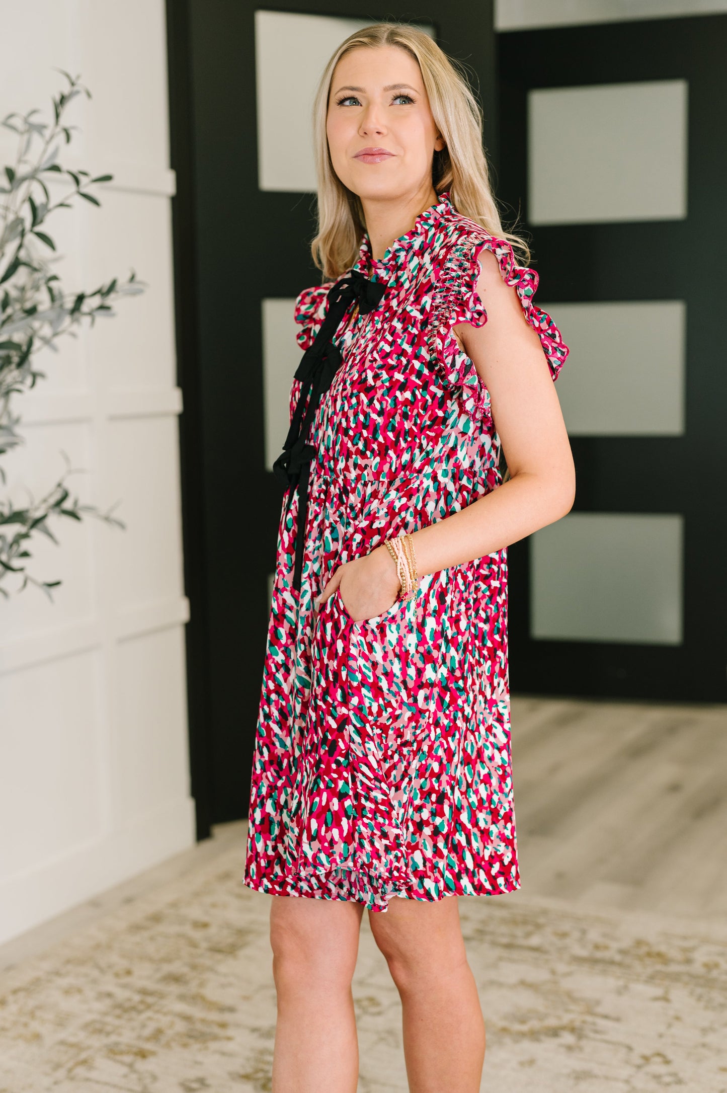 Woman wearing Jocelyn Bow Detail Dress in fuchsia print, side angle.