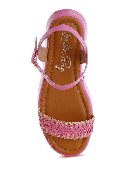View of pink raffia flatform sandals with open toe, woven straps, and cushioned footbed on a 2-inch platform heel.
