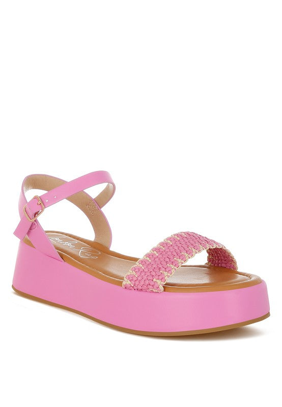 Close-up of pink raffia platform sandals with pin buckle strap and 2-inch heel, perfect for summer outfits.
