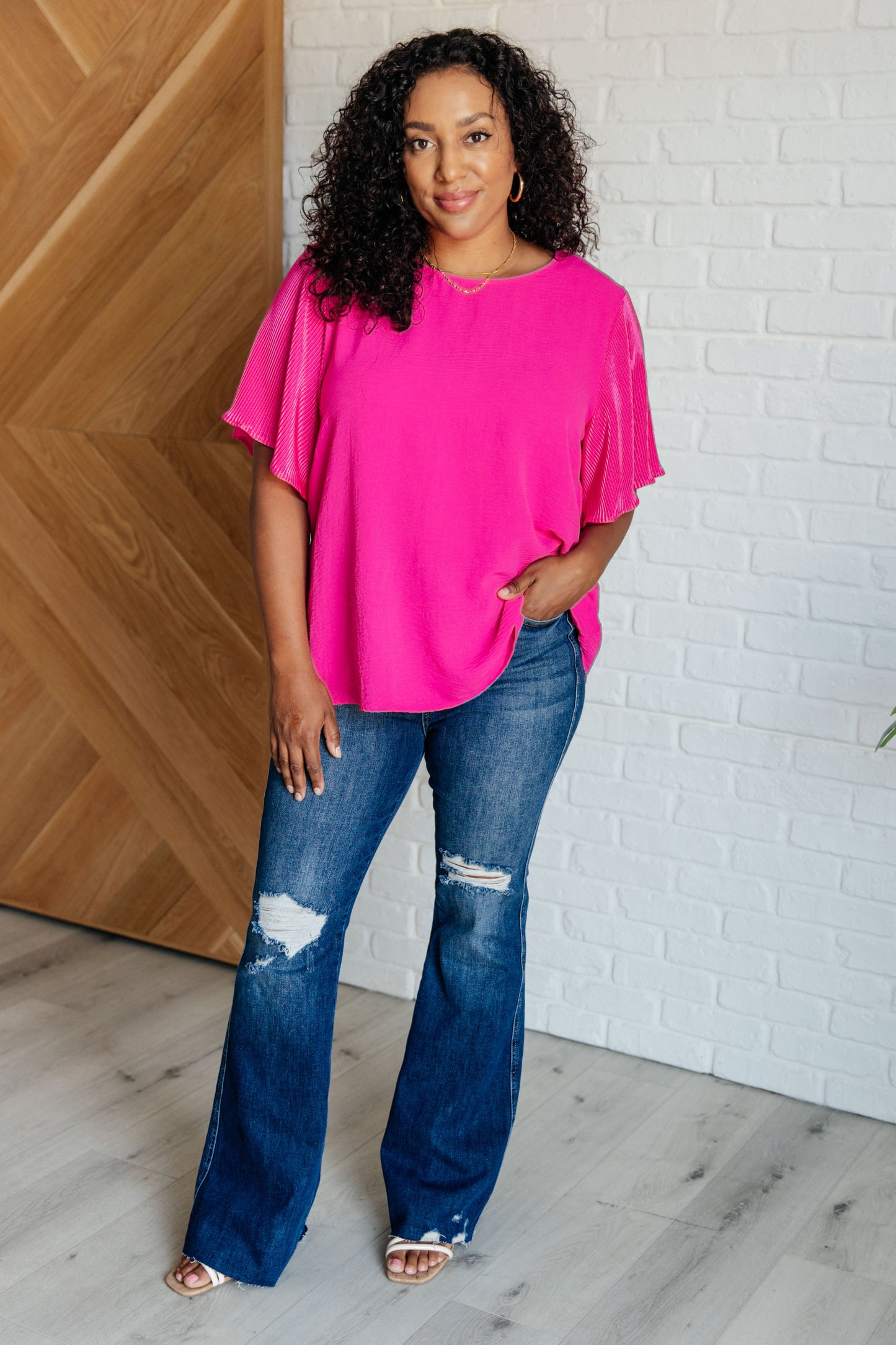 Textured pink plus size blouse with round neckline and ruffle sleeves, perfect for elevated casual looks.