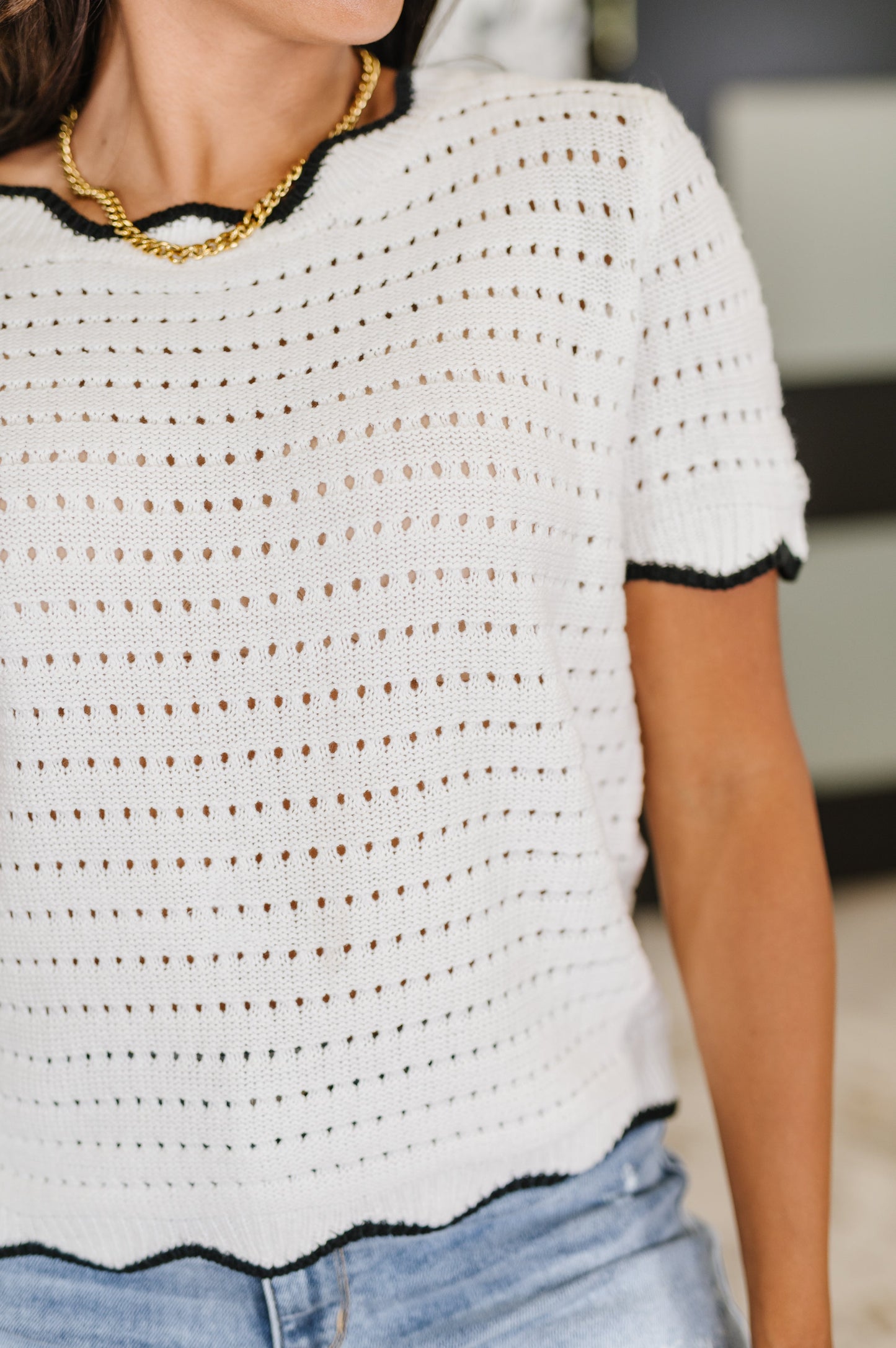 Close up of Pixie Knit Top neckline showing eyelet knit pattern and wavy contrast trim