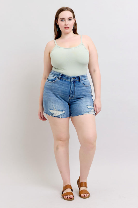 Plus size model wearing Judy Blue Charley cutoff shorts, high rise medium wash denim with raw hem casual fit.