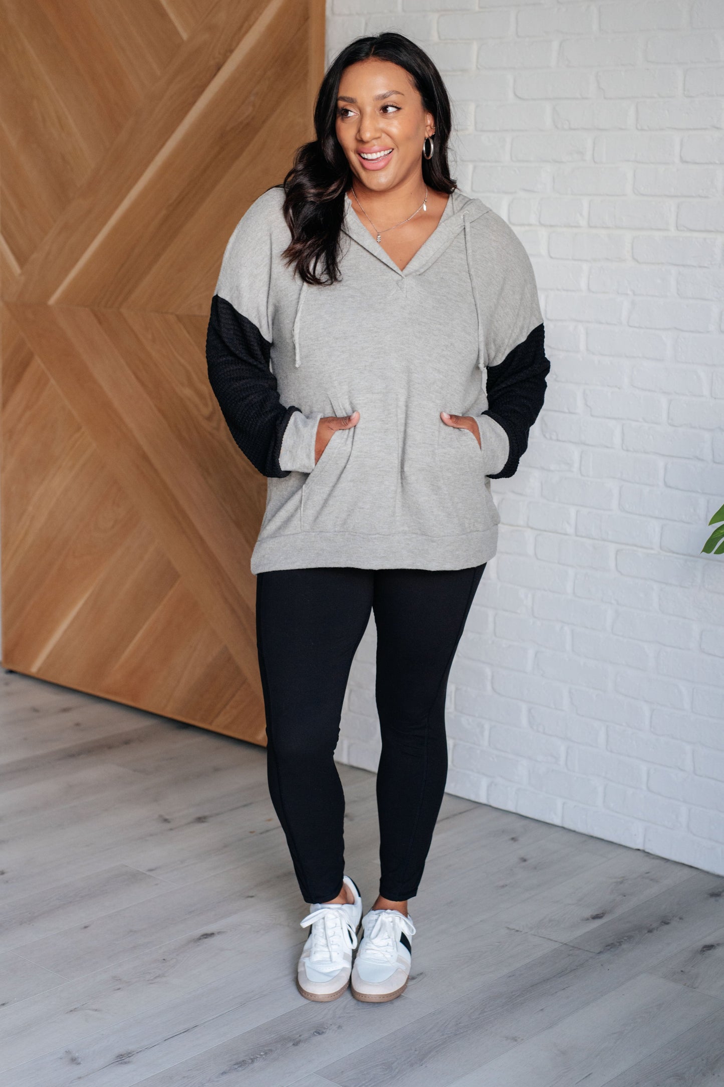 Plus size model wearing Dottie Color Block Hoodie full body, showing relaxed fit with hooded v-neckline.