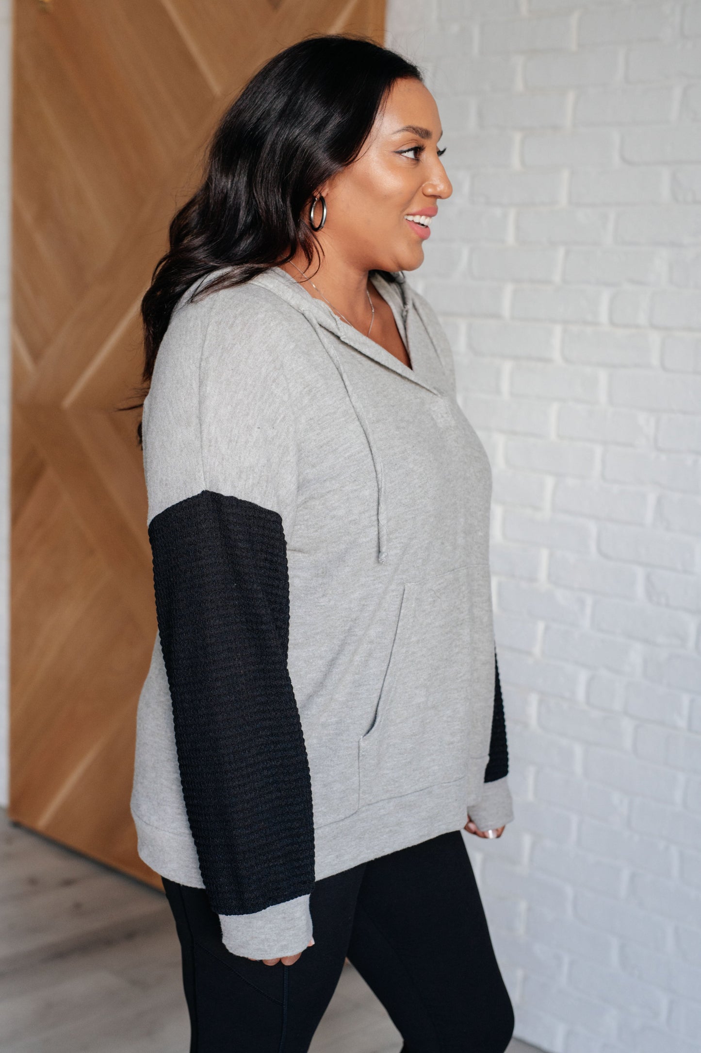 Side view of Dottie Color Block Hoodie on plus size model highlighting hood and waffle knit sleeve texture.