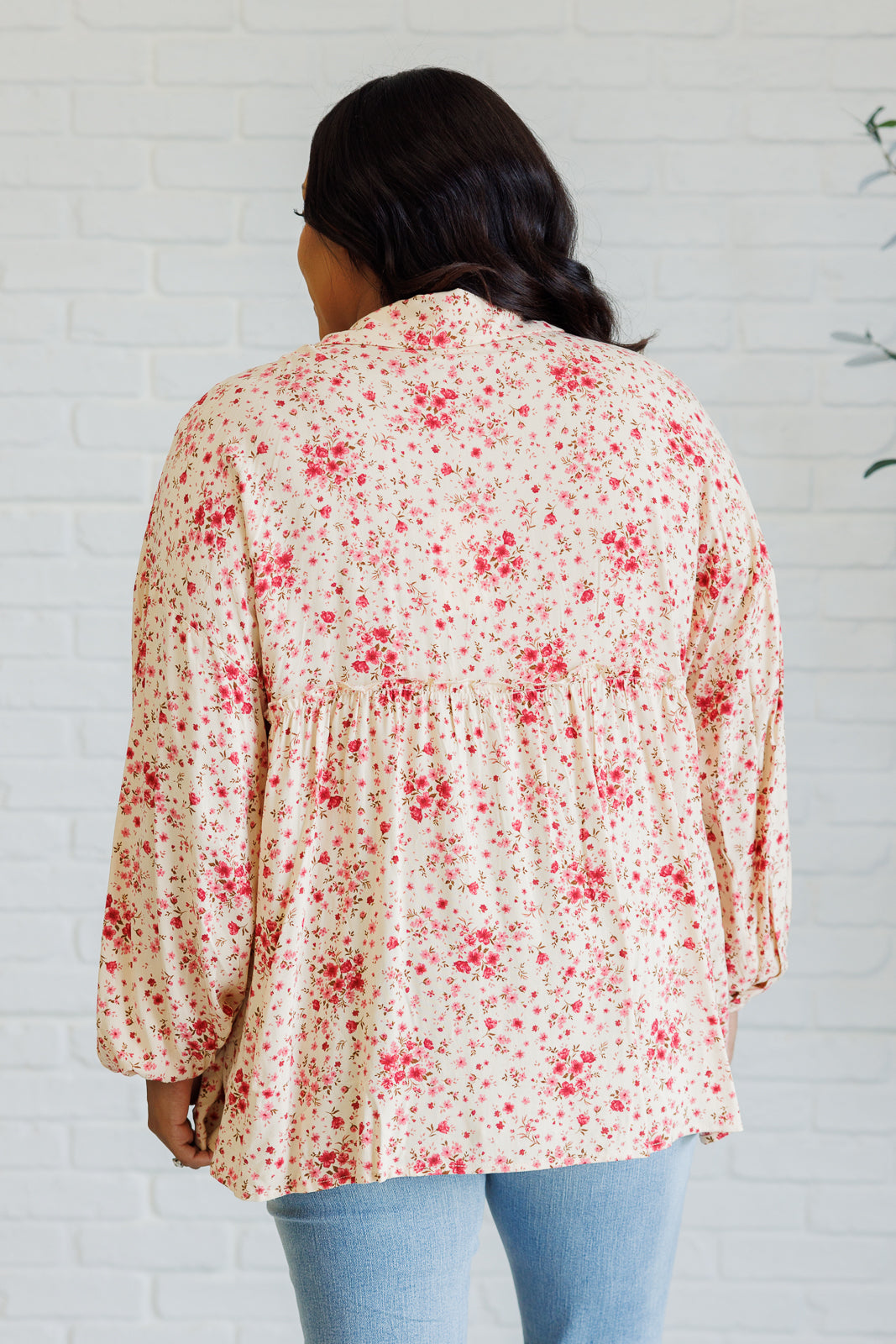 Plus size back angle of Rea floral blouse with elastic sleeve cuffs and playful ruffle accents.