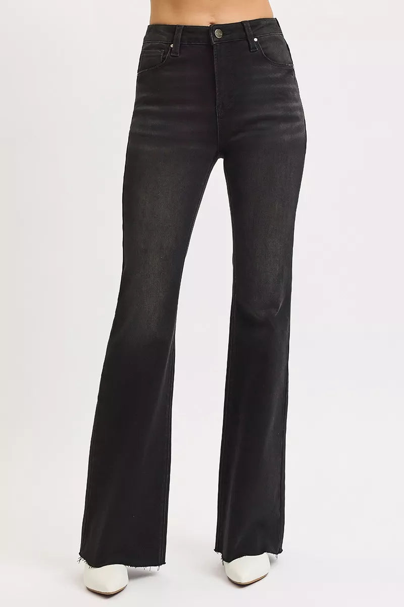 Model wearing black high rise flare jeans, styled with fitted top for chic look.
