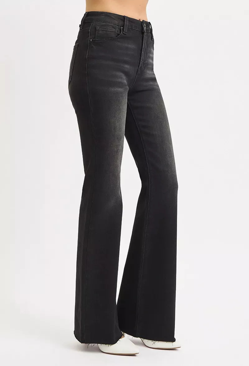 Side angle of black high rise flare jeans with raw cut hem, Risen denim fit.