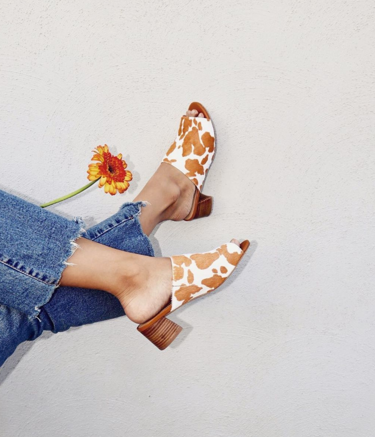 Woman wearing Prairie Tan Cowhide Slides, styled with denim for casual chic look.