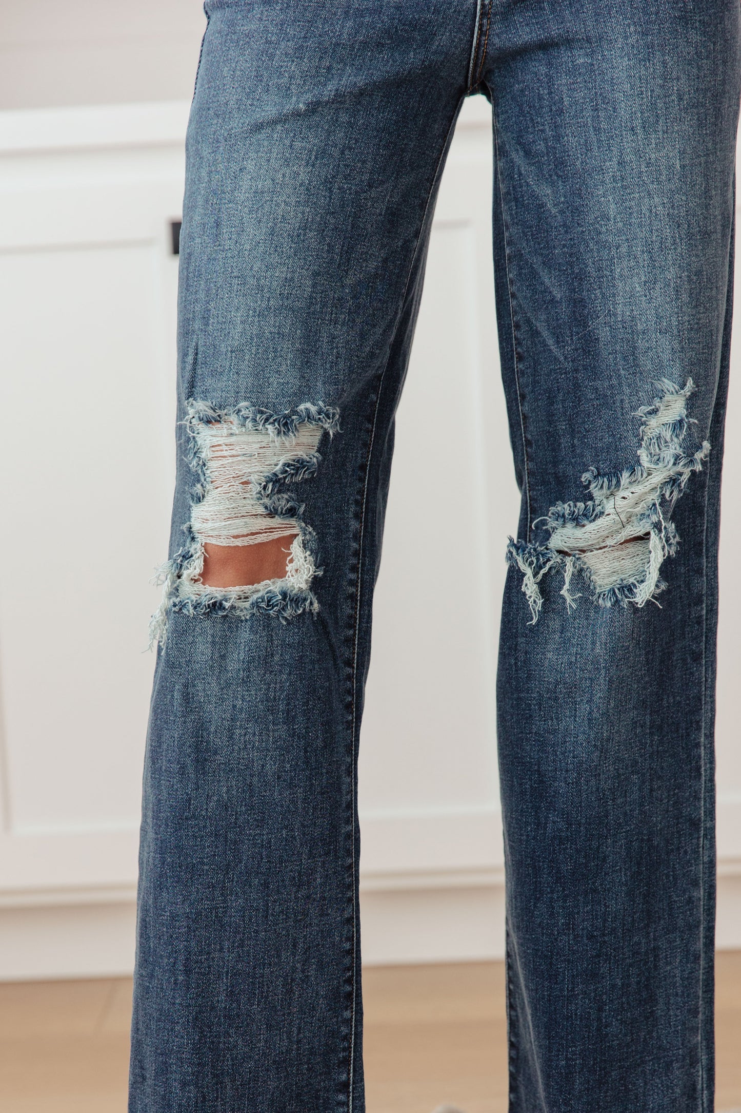 Close-up detail of distressing and chewed hem on Rose High Rise 90's Straight Jeans in dark wash.