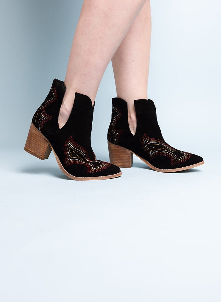 Woman wearing Journee Black Suede Ankle Boots with western stitching and ankle cutout.