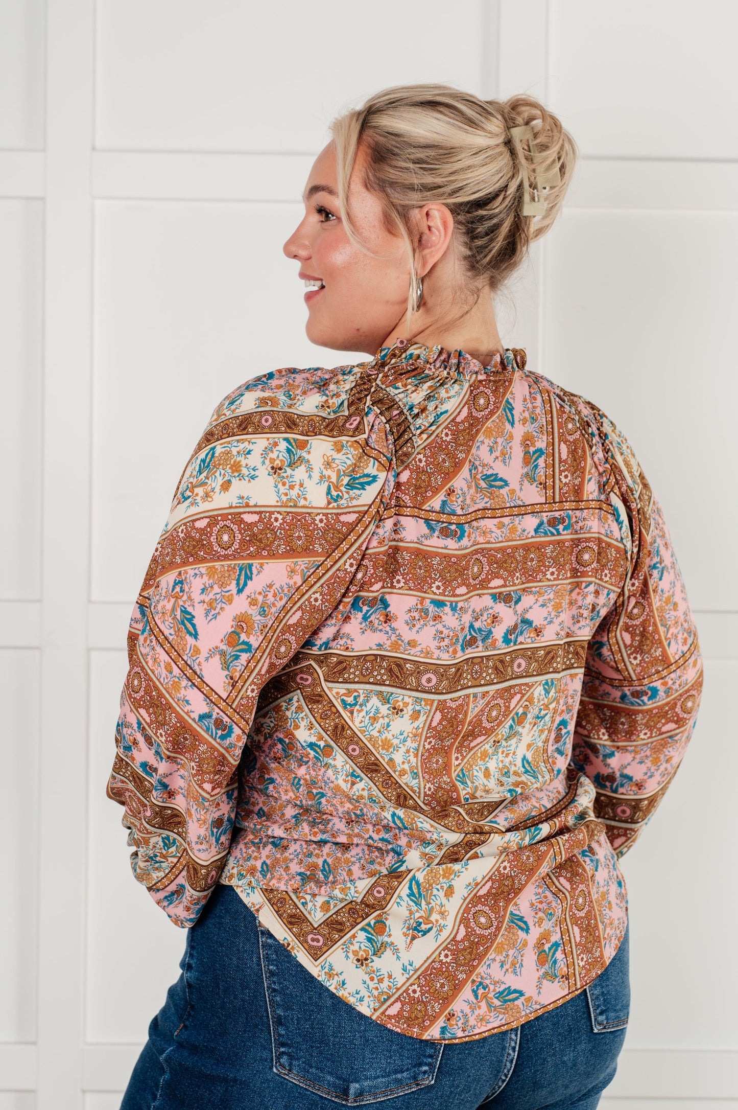 Plus-size model in Elise blouse turned slightly, highlighting flowy hemline.