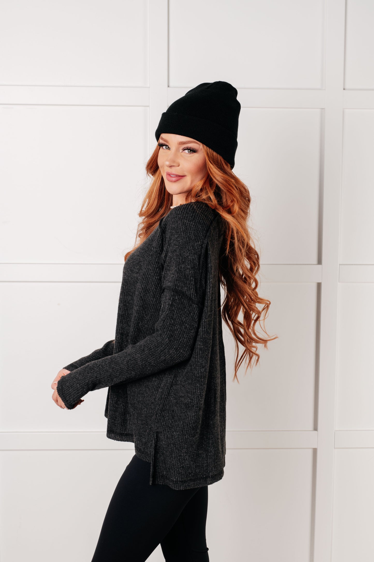 Side view of Simon Ribbed Hacci Sweater in black with exposed seams, side slits, and relaxed fit sleeves.