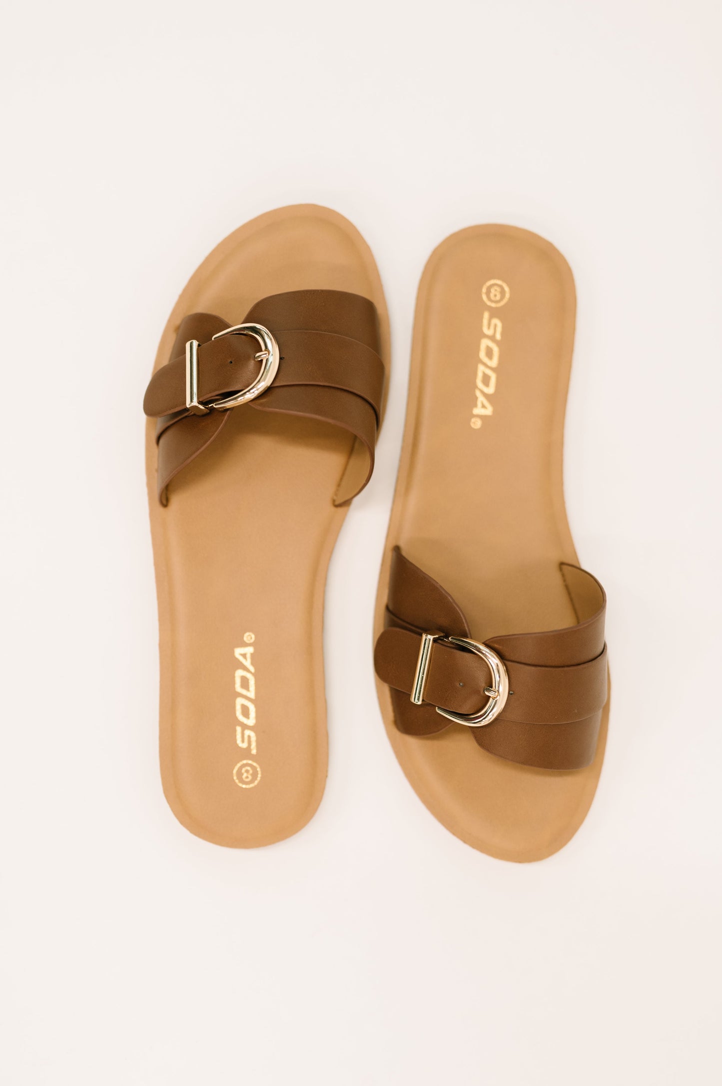 Flat lay of Siran Dark Tan Slip-On Sandals by Soda faux leather strap and neutral tone.