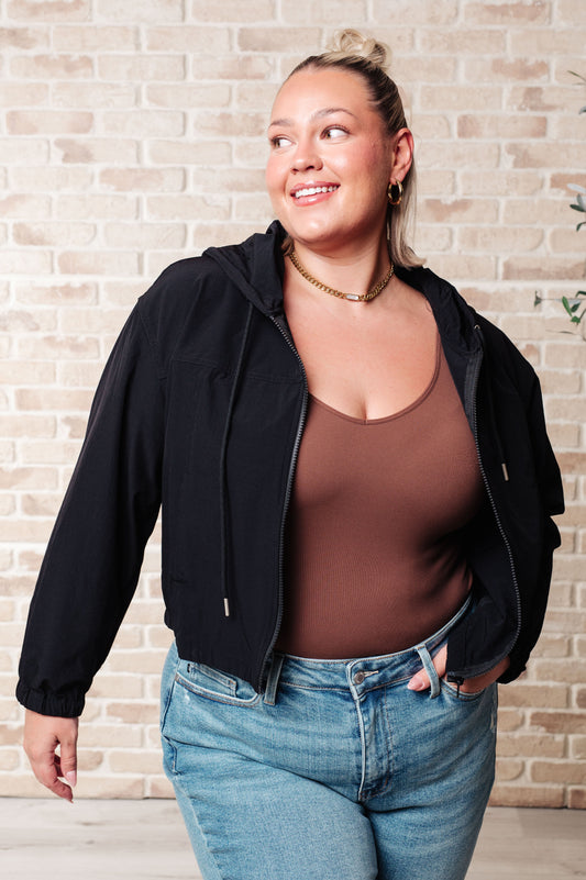 Plus size model wearing Sky Zip Up in Black featuring hood and front zipper.
