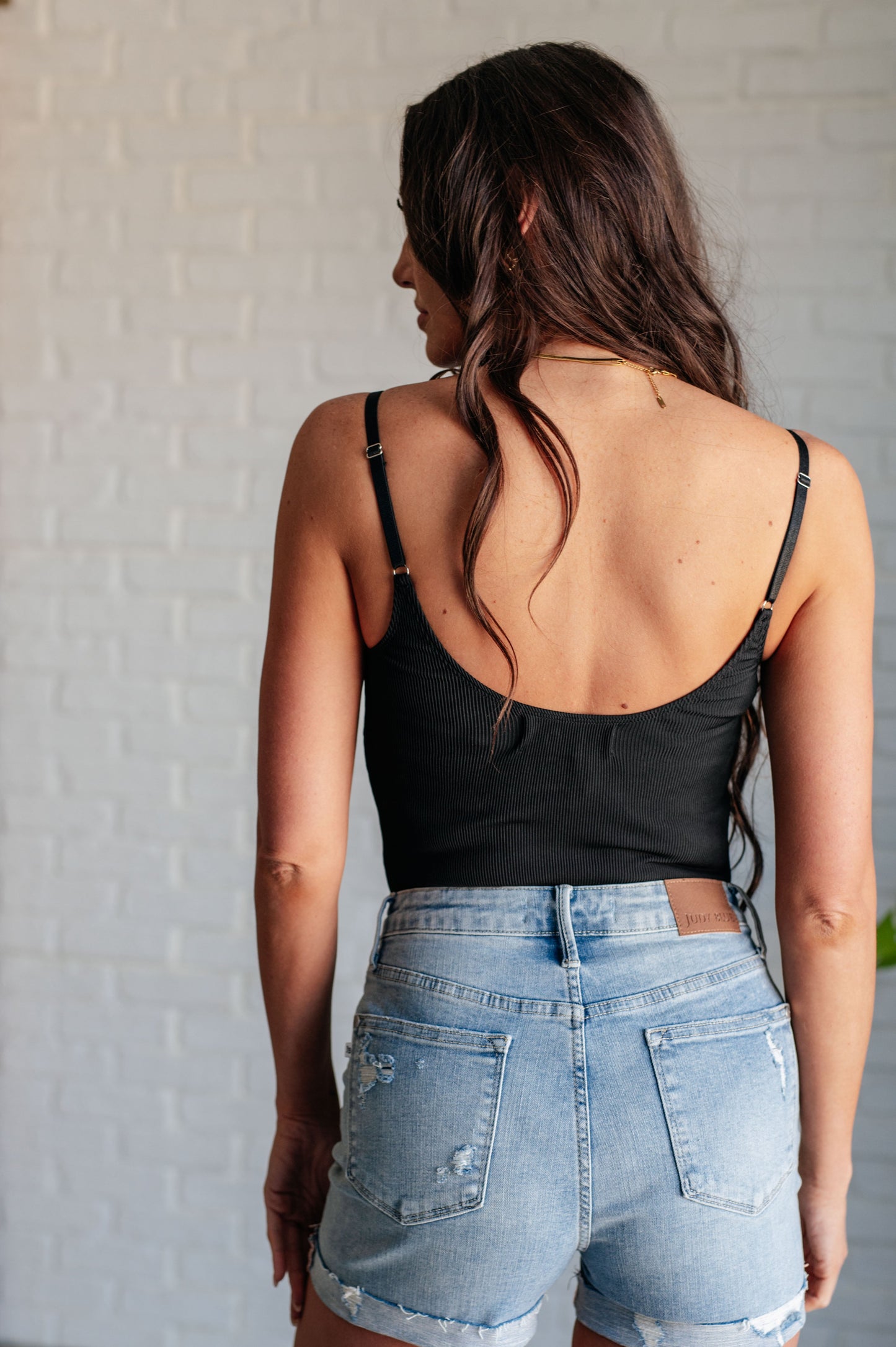 Back view of Saylor Black Ribbed Knit Bodysuit with cheeky thong cut and slim adjustable straps.