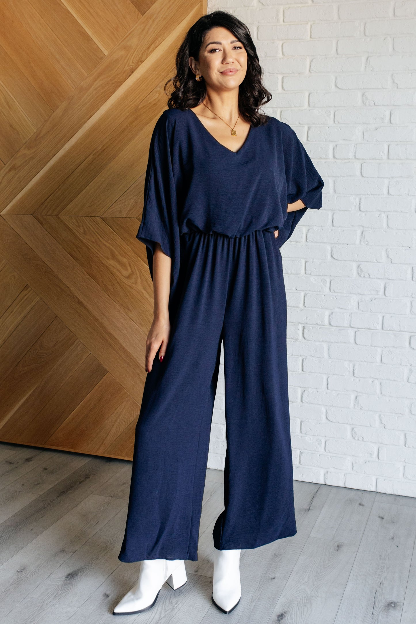 Woman wearing navy Sonya Wide Leg Jumpsuit with v-neckline and kimono sleeves, casual front view.