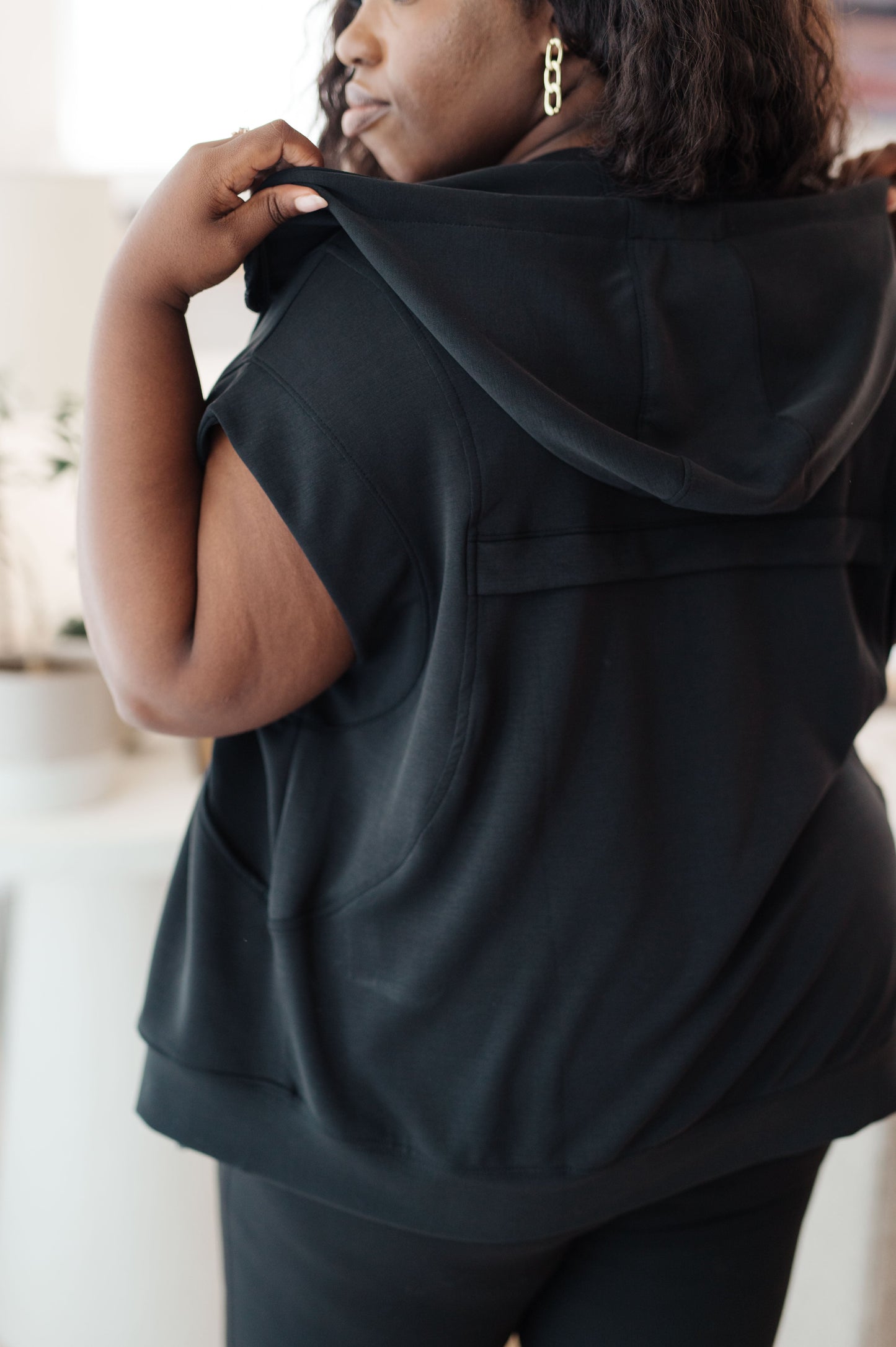 Back view of plus-sized model wearing the Isabella Sleeveless Hoodie, emphasizing the hood and relaxed silhouette.