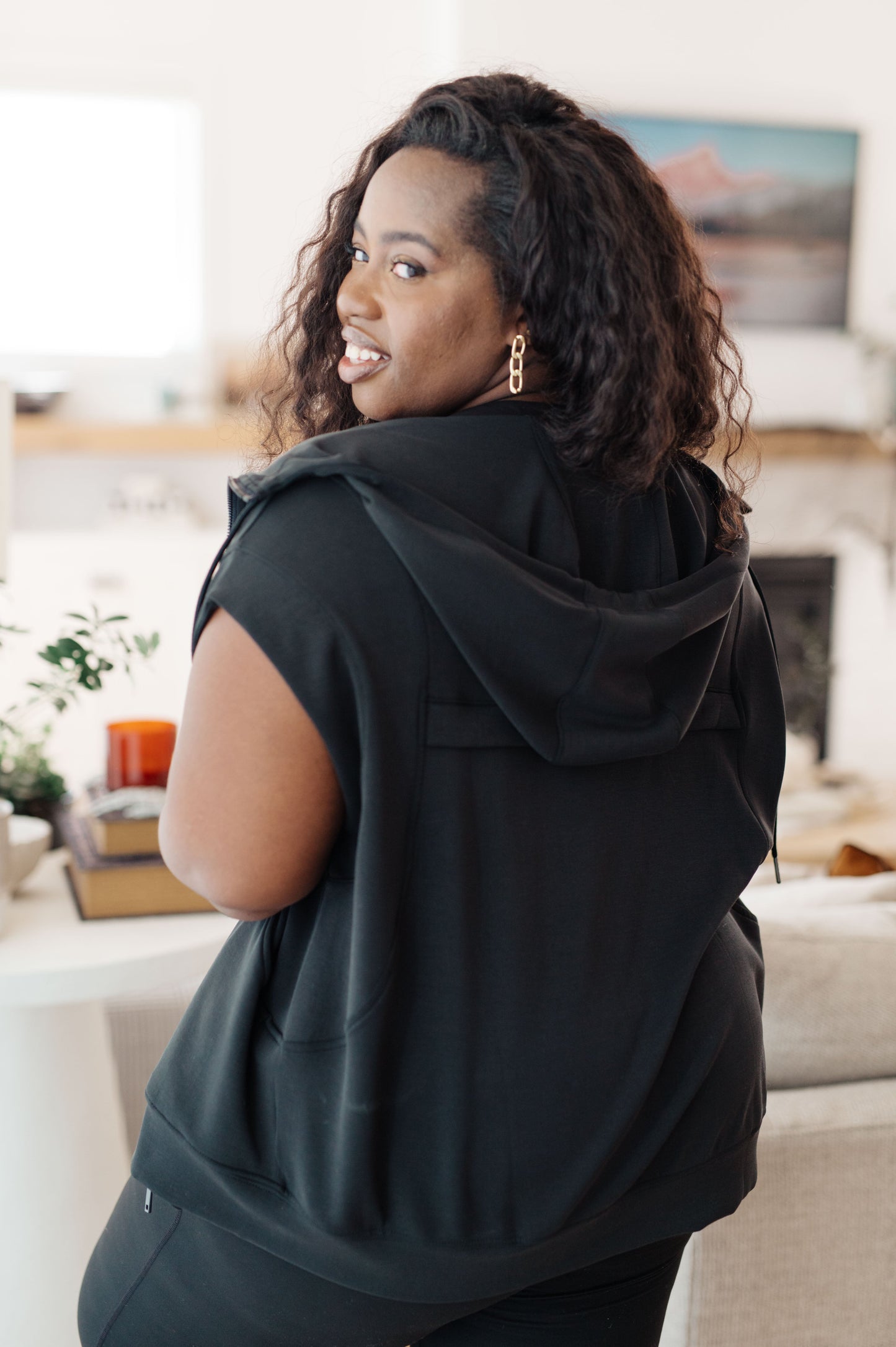 Back view of plus-sized model wearing the Isabella Sleeveless Hoodie, showcasing the smooth fabric and structured back design.