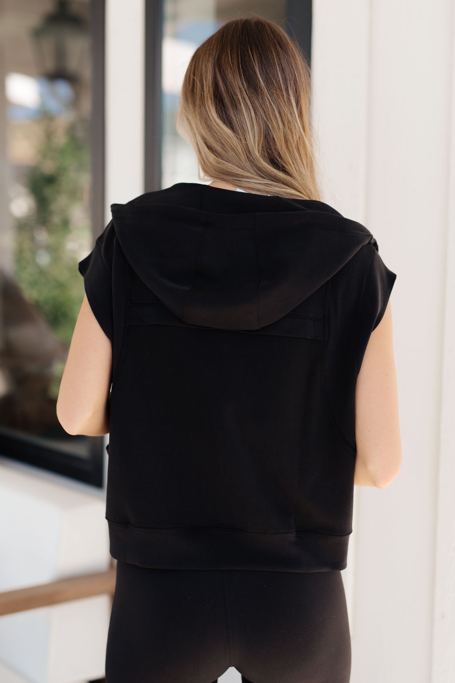 Standard-sized model showing the back of the Isabella Sleeveless Hoodie, highlighting its sporty fit and functional hood.