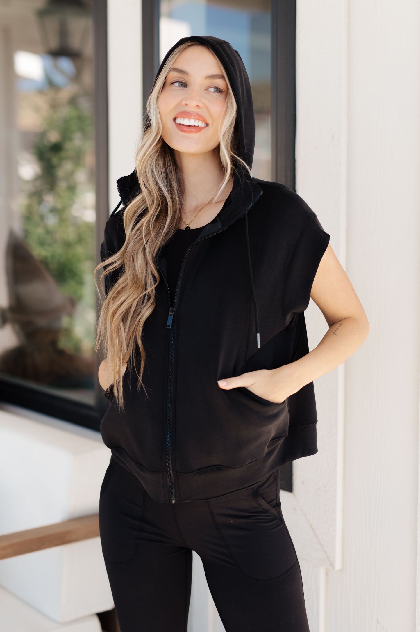 Standard-sized model wearing the Isabella Sleeveless Hoodie with the hood up, displaying its adjustable drawstring feature.