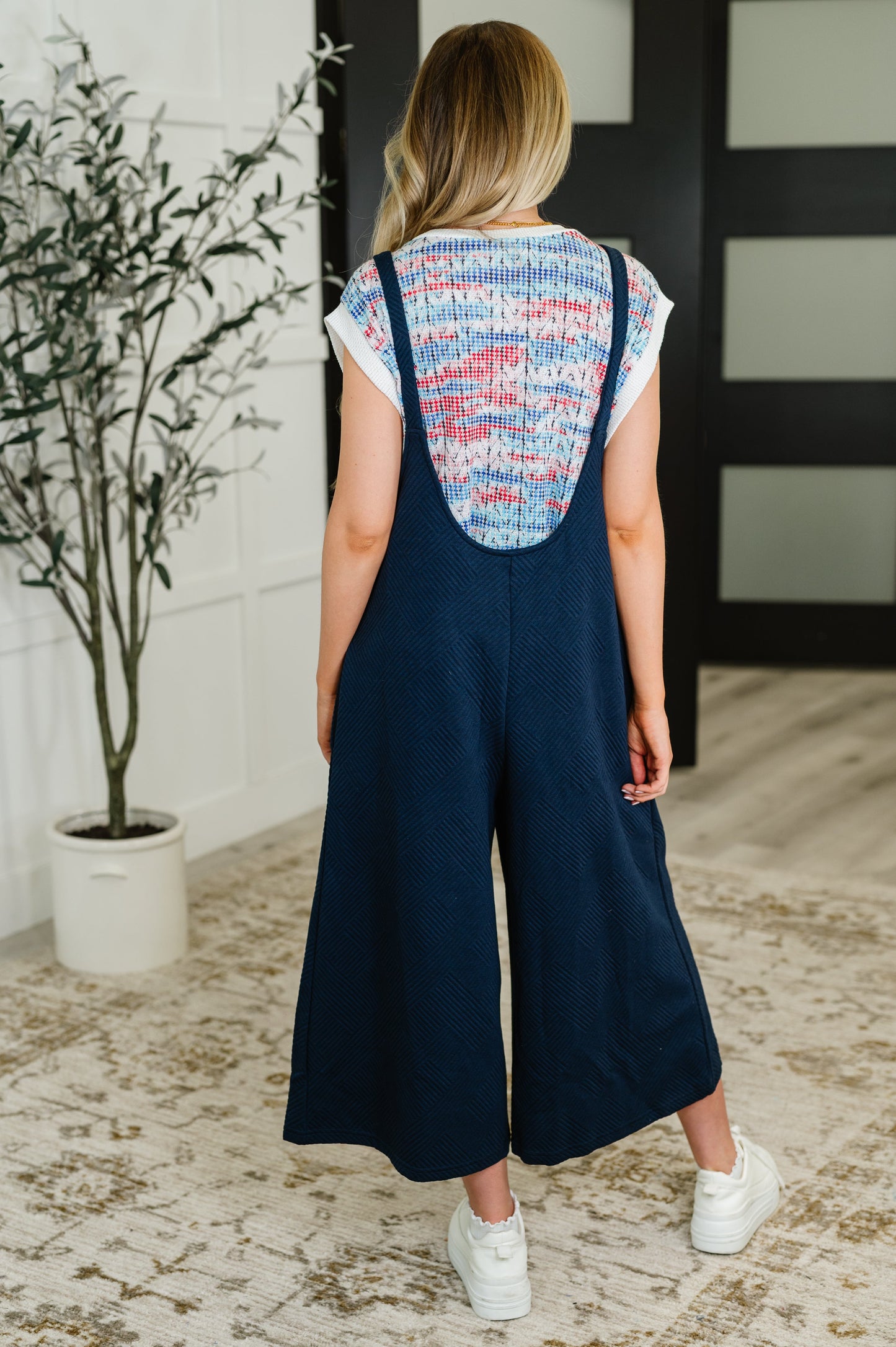 Back view of Lottie Navy Jumpsuit showing quilted knit fabric, wide-leg silhouette, tie straps, and functional side pockets.