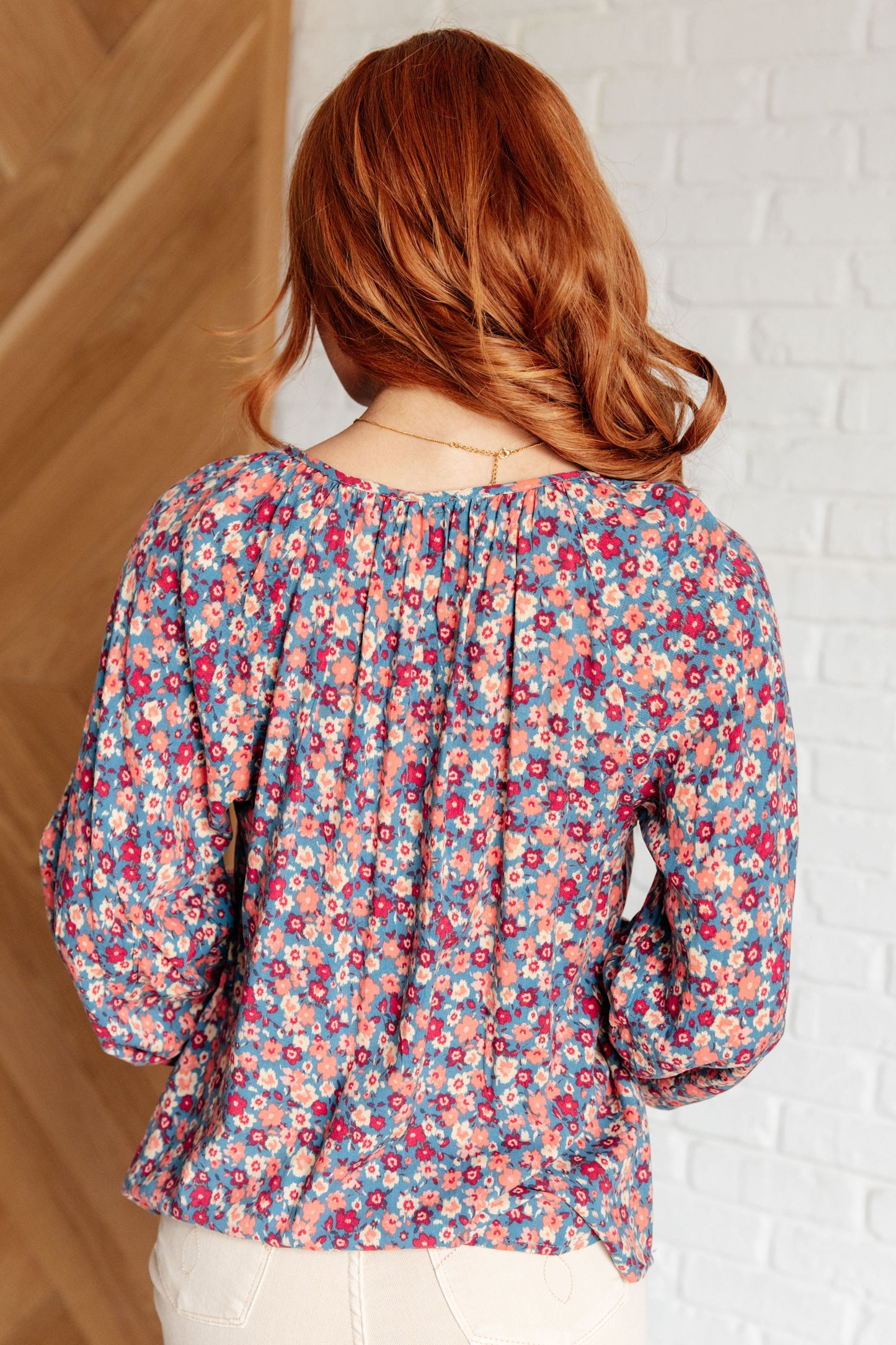 Back view of Krychele Floral Blouse showing denim background with pink florals and gathered relaxed fit.