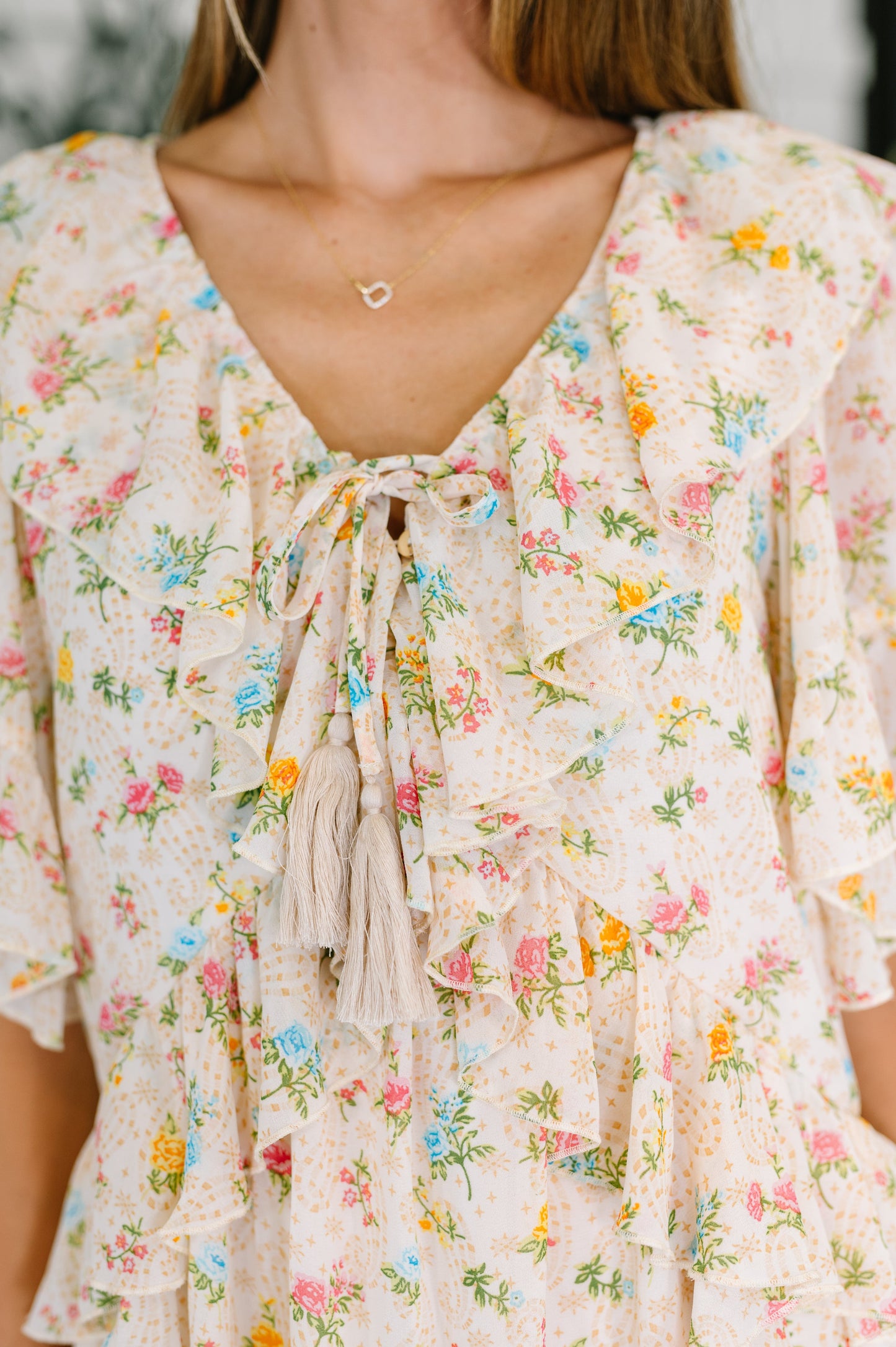 Close-up view of the Addison Boho Floral Dress highlighting the ruffle trim, tassel ties, and floral chiffon fabric.