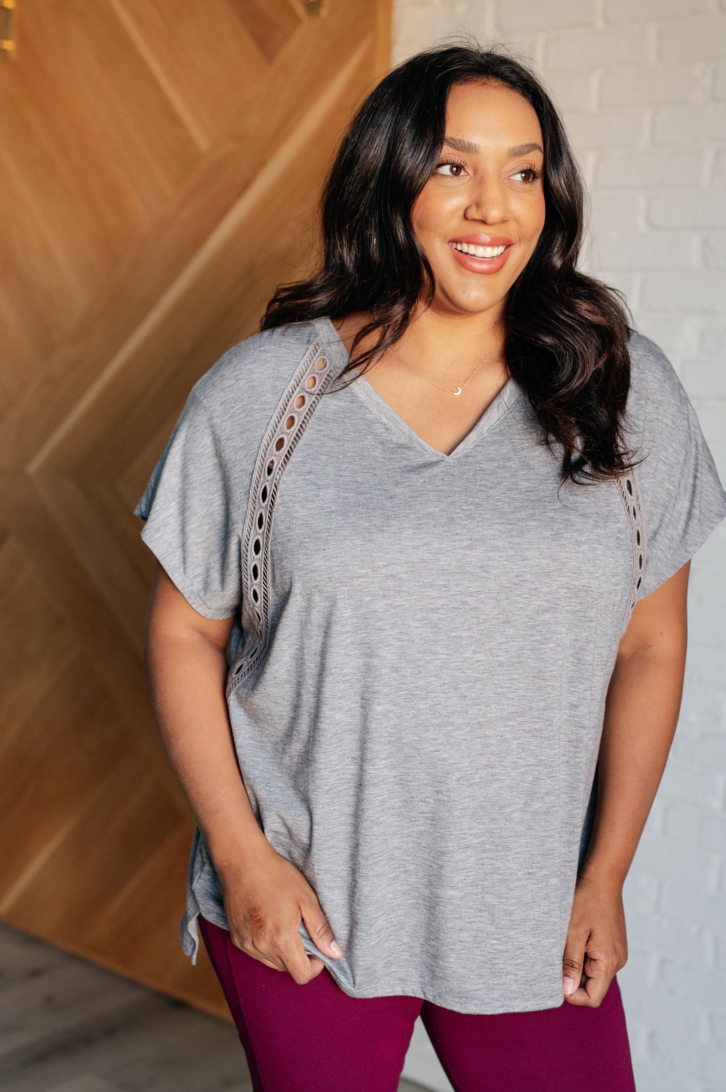 Women's Eyelet Trim Top in gray with V-neckline, batwing sleeves, eyelet trim detailing, and a stepped hemline.