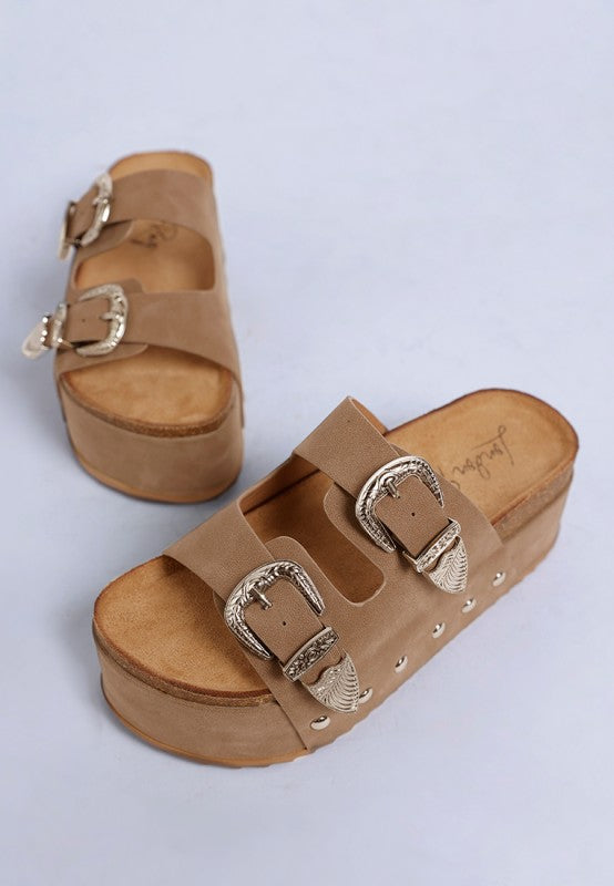 Taupe faux leather flatform slip ons with carved buckle straps and round open toe front view.