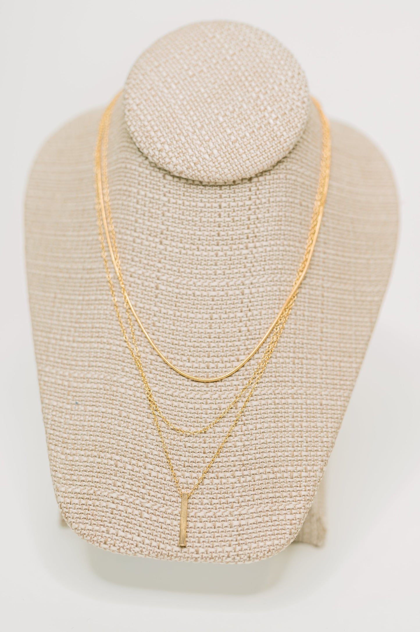 Signature Gold Layered Necklace displayed on jewelry stand